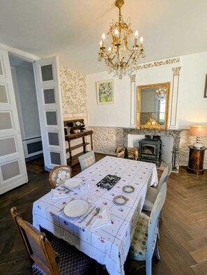 Une salle à manger avec un lustre, une cheminée et un miroir au mur.