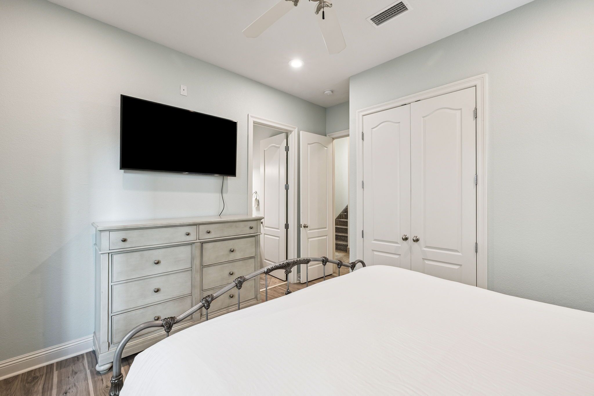 A bedroom with a bed, a dresser, a television, and a closet.
