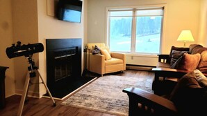 Ein Wohnzimmer mit Kamin, einer Couch, einem Sessel, einer Lampe und einem Teleskop.