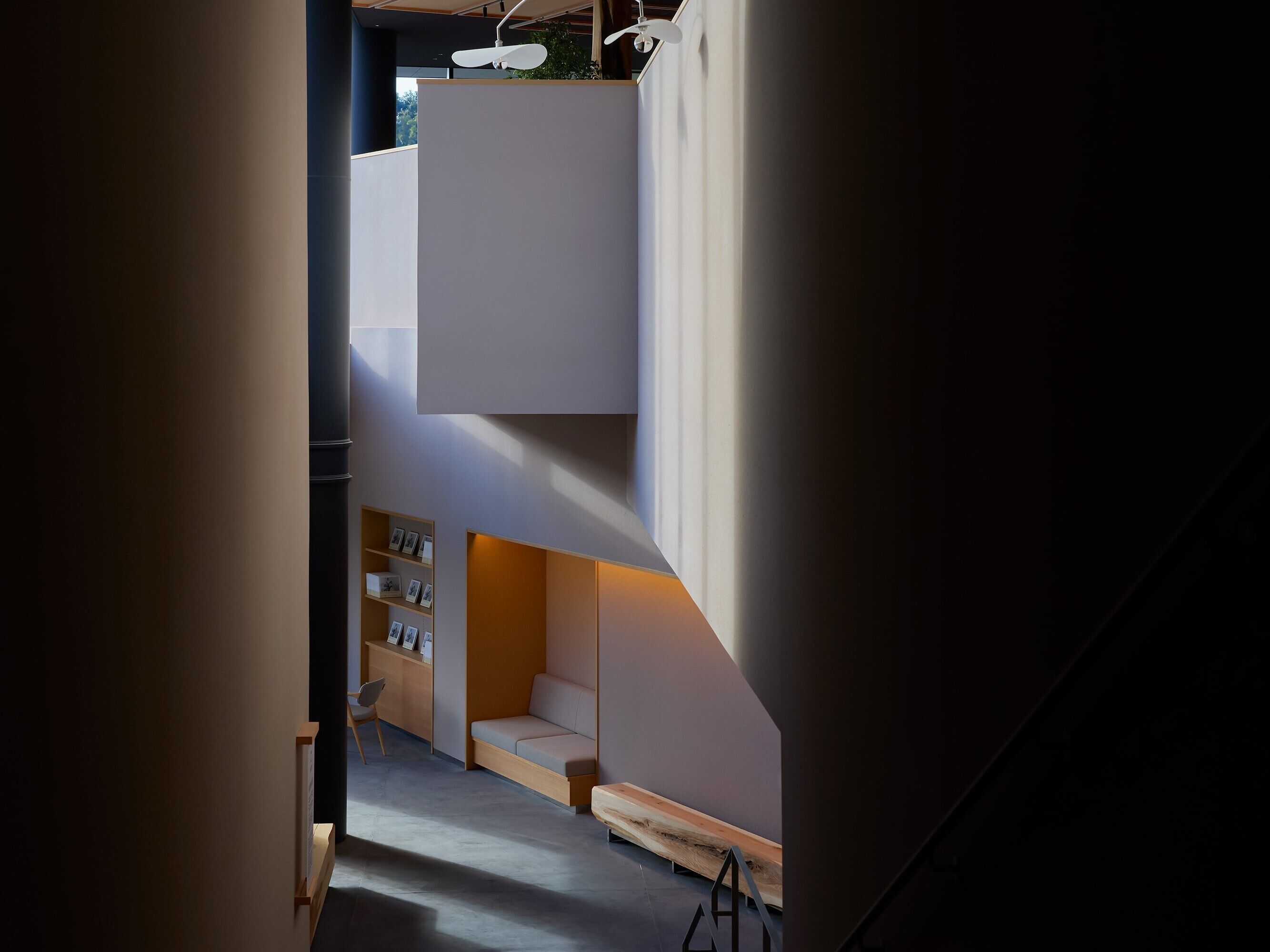 Un intérieur moderne comprenant un escalier, un coin salon et une étagère ornée de tableaux encadrés.
