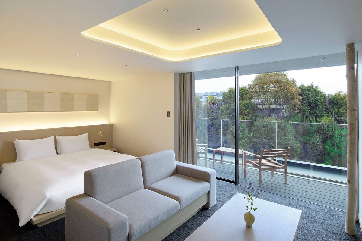 Ein modernes Hotelzimmer mit Bett, Sofa und einem Balkon mit Blick.