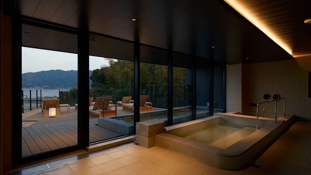 A modern spa with a large glass wall, a hot tub, and wooden deck furniture. - HOTEL FORK & KNIFE Miyajima (Hatsukaichi)
