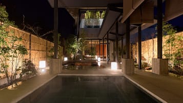 Un espace piscine extérieur moderne, offrant une vue dégagée sur le bassin, agrémenté de plantes et éclairé par un système d’éclairage d’ambiance.