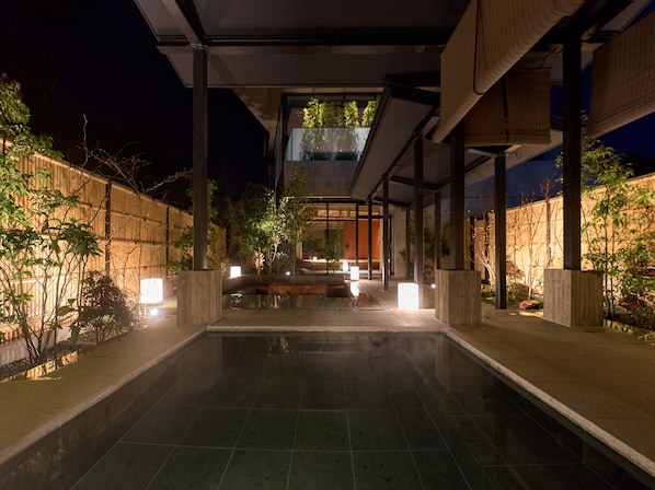A modern outdoor pool area with a clear view of the pool, surrounded by plants and illuminated by ambient lighting. - HOTEL FORK & KNIFE Miyajima (Hatsukaichi)