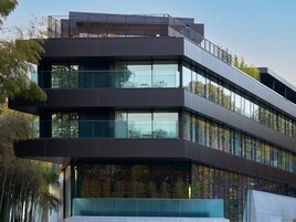 A modern multi-story building with large windows and a balcony.