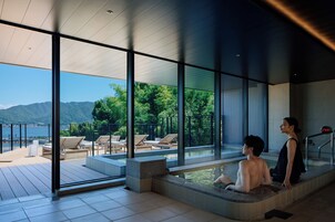 A modern spa area with a hot tub and lounge chairs overlooking a scenic mountain view.