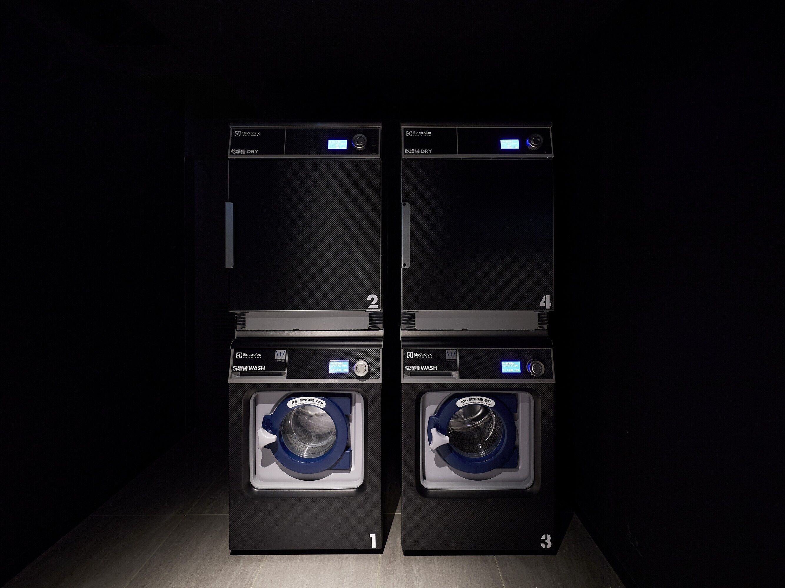 Two black washing machines with digital displays, labeled 'Electrolux' and 'WASH' mode.