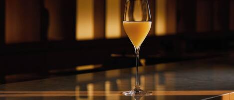 A glass of orange juice on a bar counter with a blurred background of shelves.