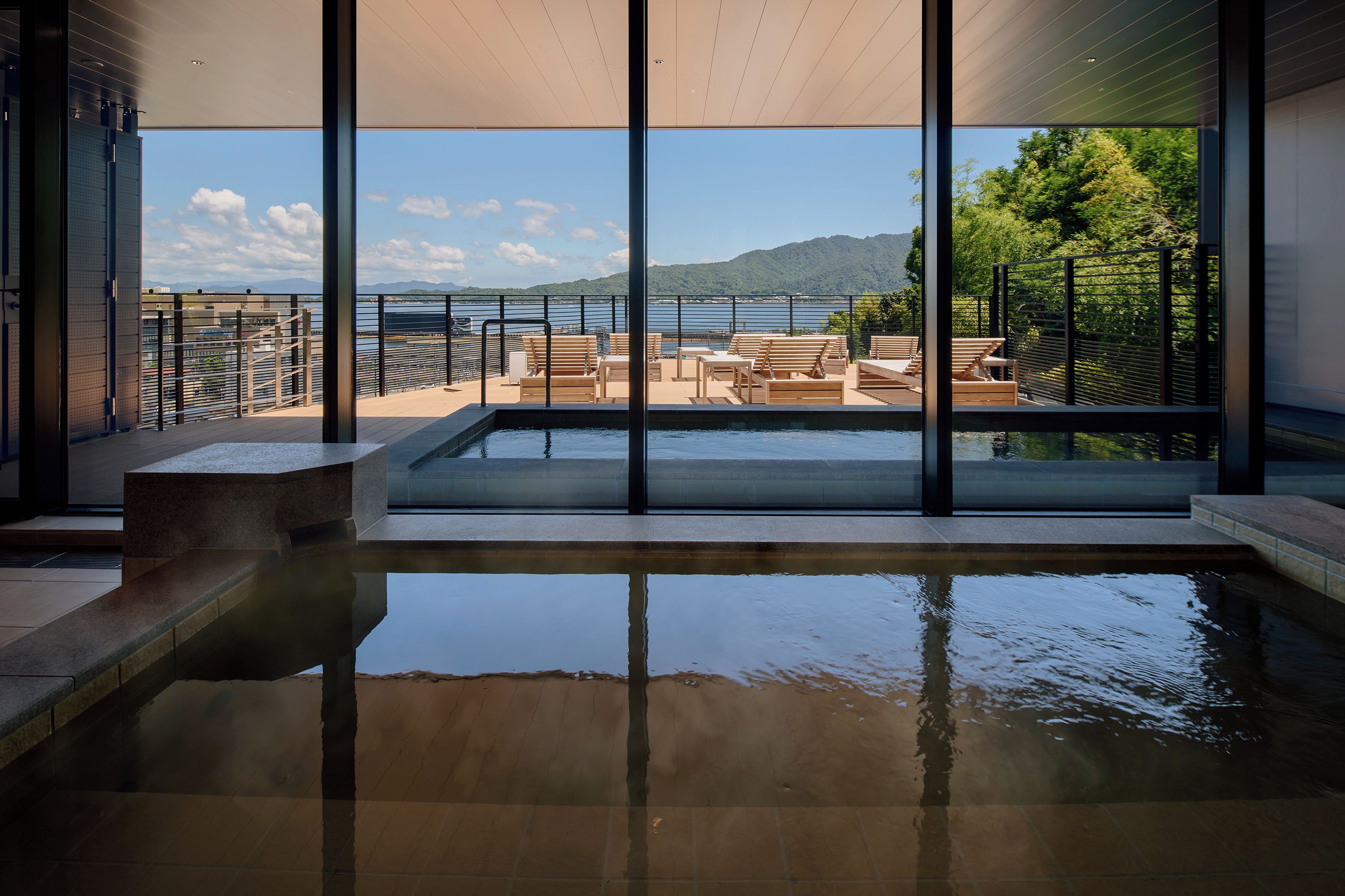 A pool area with a view of the sea and mountains.