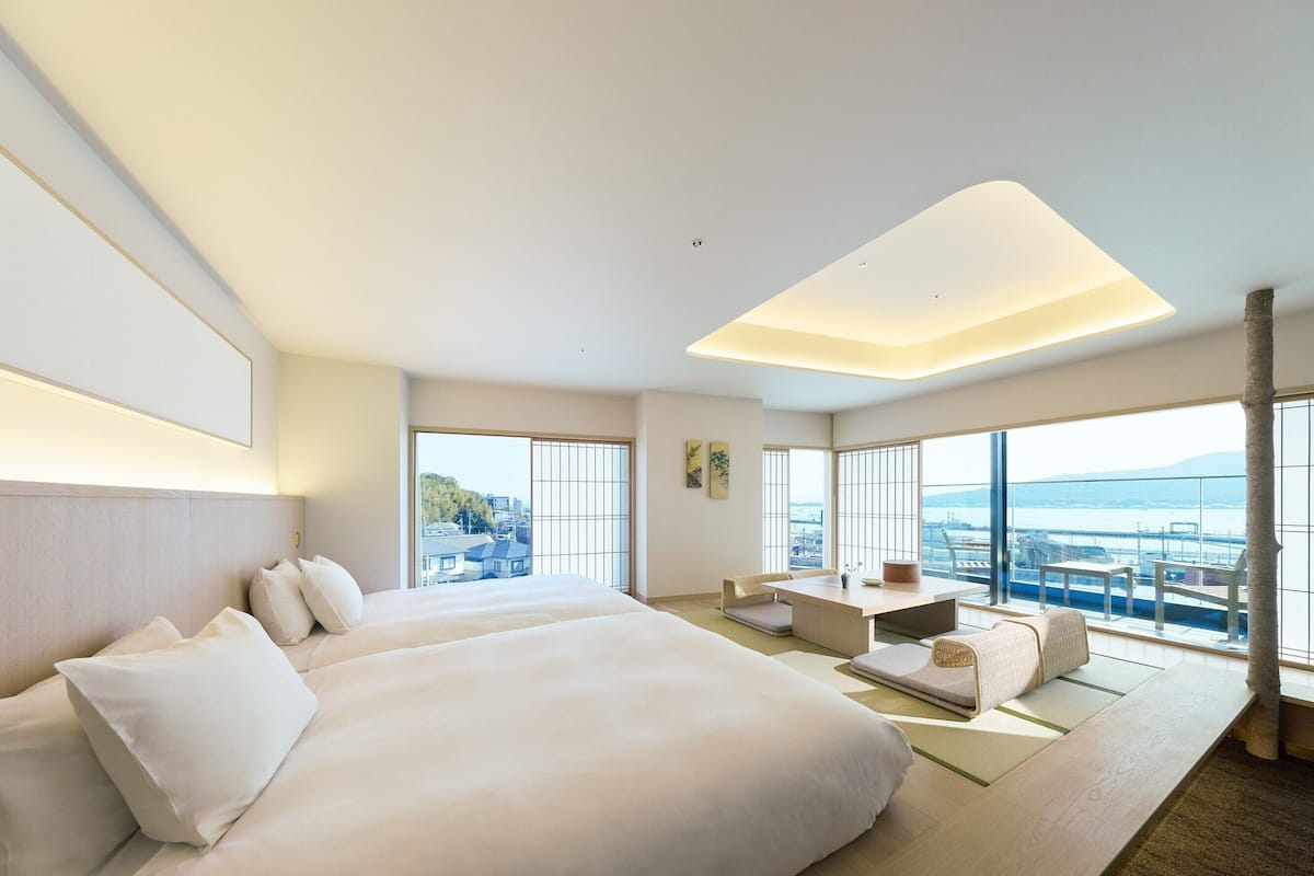 Ein modernes Hotelzimmer mit einem großen Bett, einer Sitzecke und Blick auf die Stadt.