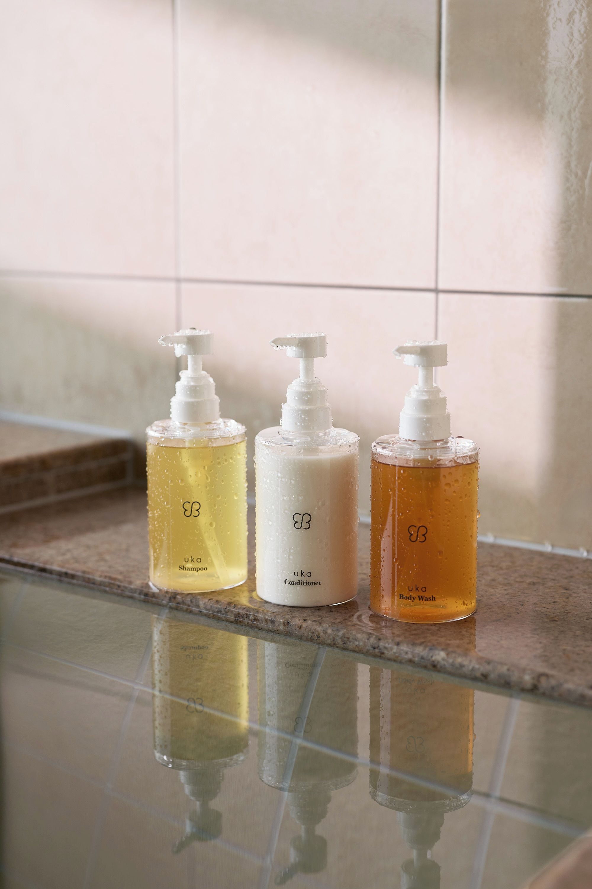 Three bottles of liquid on a reflective surface.