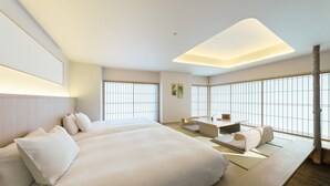 A modern hotel room with a large bed, a small table, and a seating area. - HOTEL FORK & KNIFE Miyajima (Hatsukaichi)