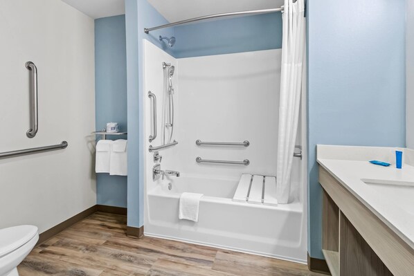 A bathroom with a shower, toilet, and sink, equipped with handrails and grab bars. - WoodSpring Suites Washington Meadowlands PA (Washington)