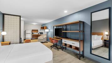 A hotel room with a bed, desk, chair, TV, and a large mirror.