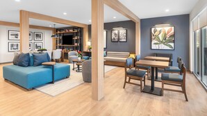 Een modern interieur met een blauwe bank, een houten eettafel en stoelen, een boekenkast en ingekaderde foto's aan de muur.