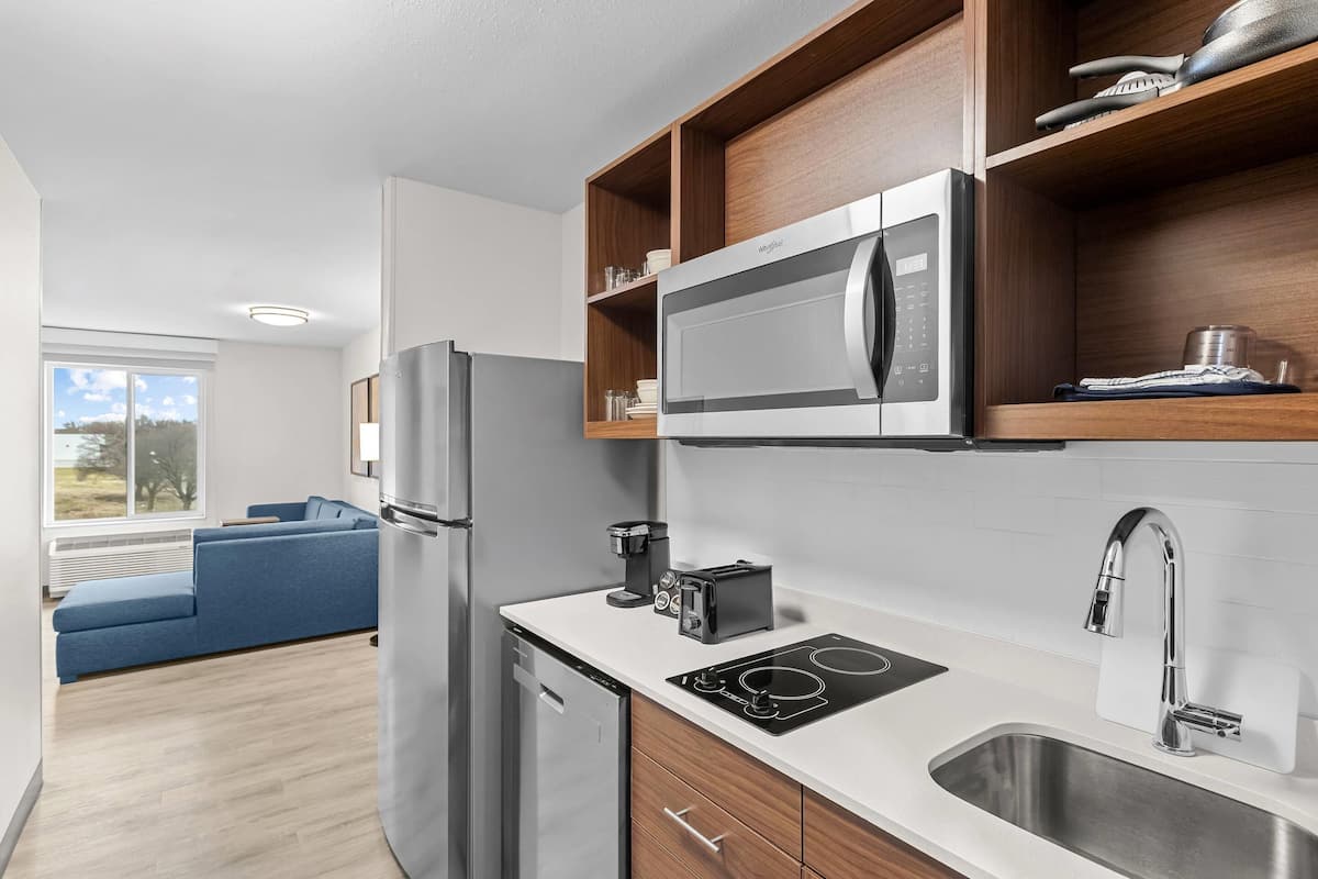 A modern kitchen with a built-in microwave, a coffee maker, and a sink.