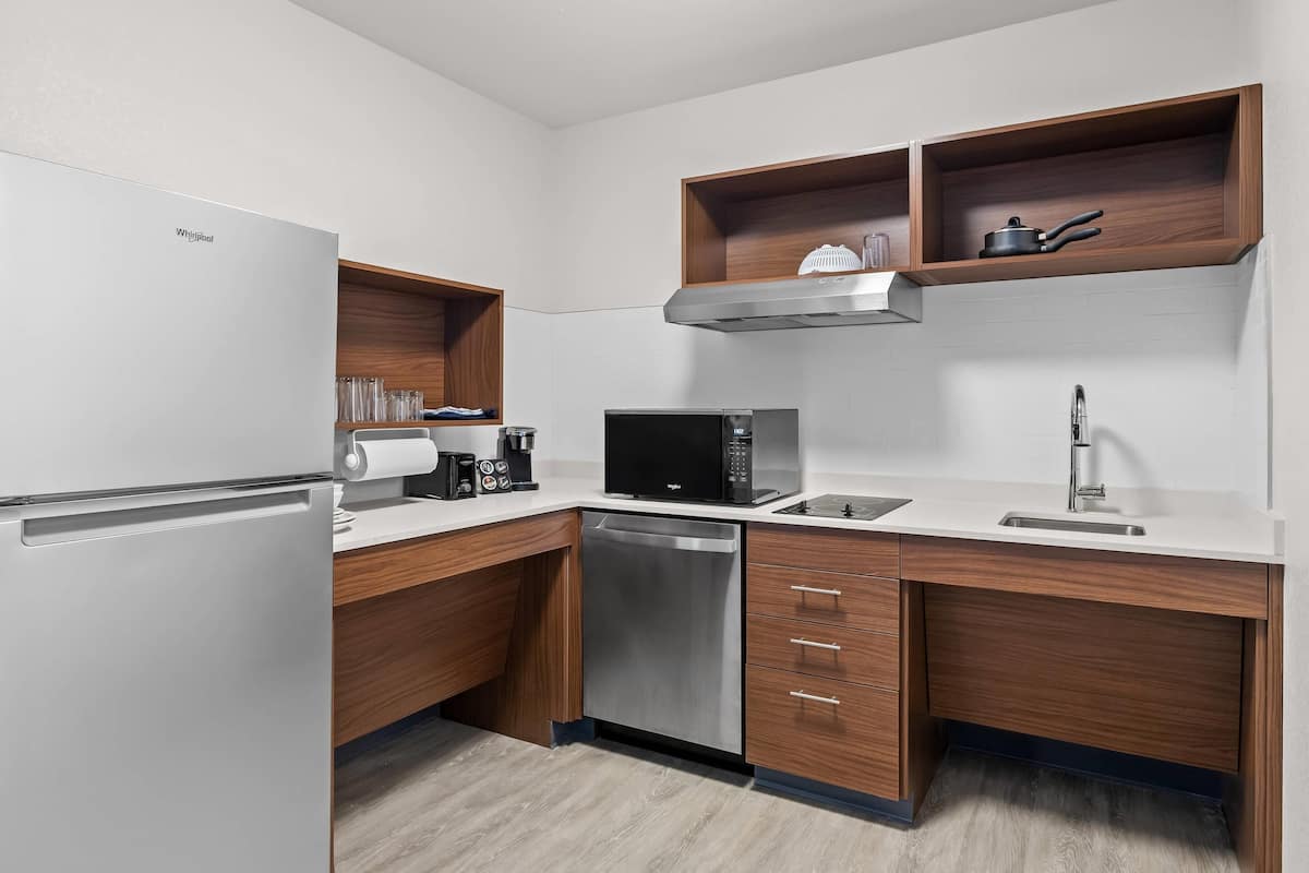 A modern kitchen with a refrigerator, dishwasher, microwave, and wooden cabinets.