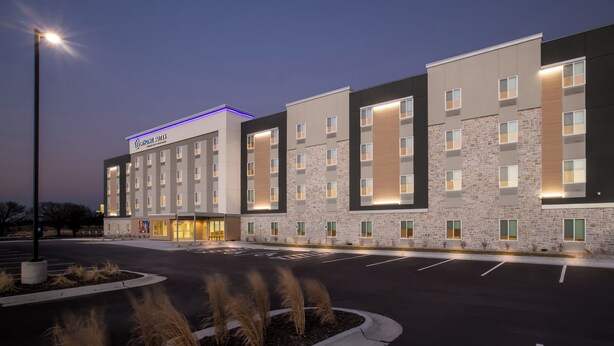 Een modern hotel met een gevel van natuursteen, meerdere verdiepingen en een goed verlichte entree.