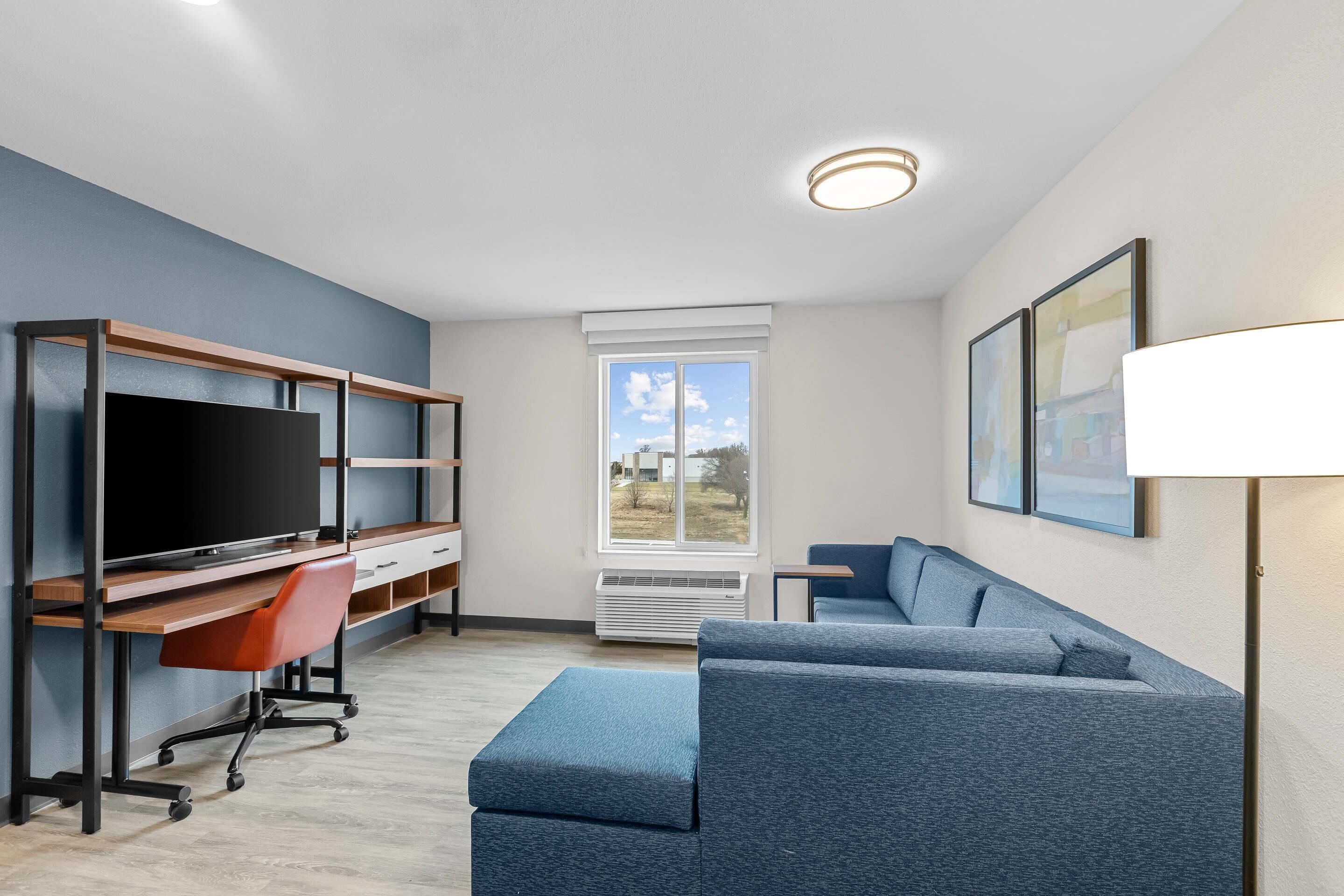 A modern living room with a TV, desk, and blue sofa.