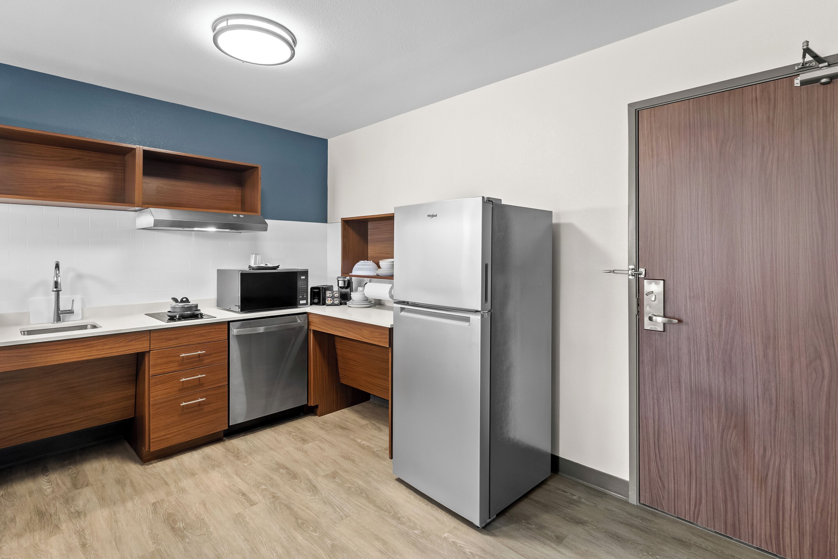 Una cocina moderna con armarios de madera, un refrigerador de acero inoxidable, un microondas y un lavavajillas.
