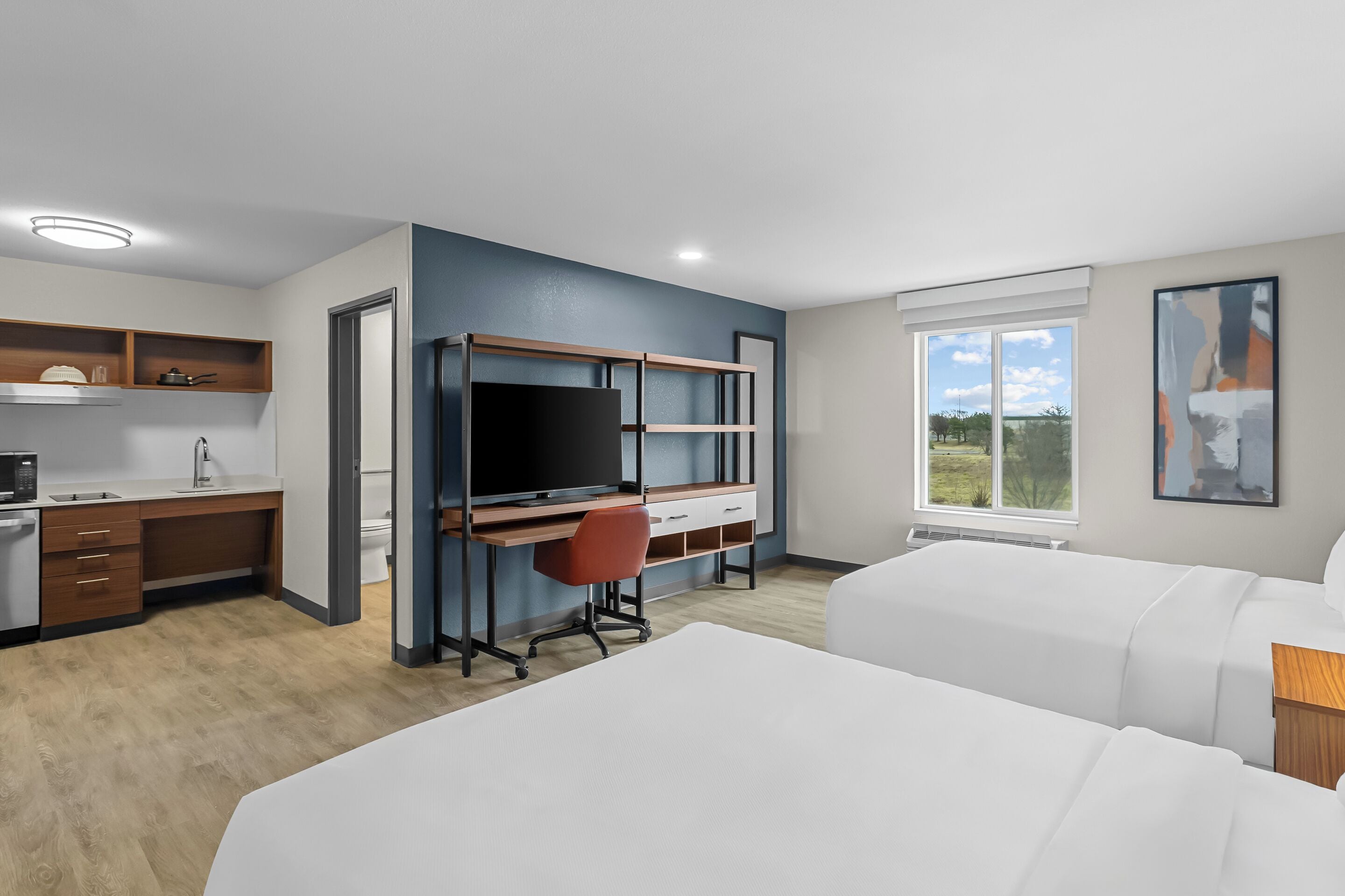 Habitación de hotel con escritorio, televisión, cama y ventana con vistas.