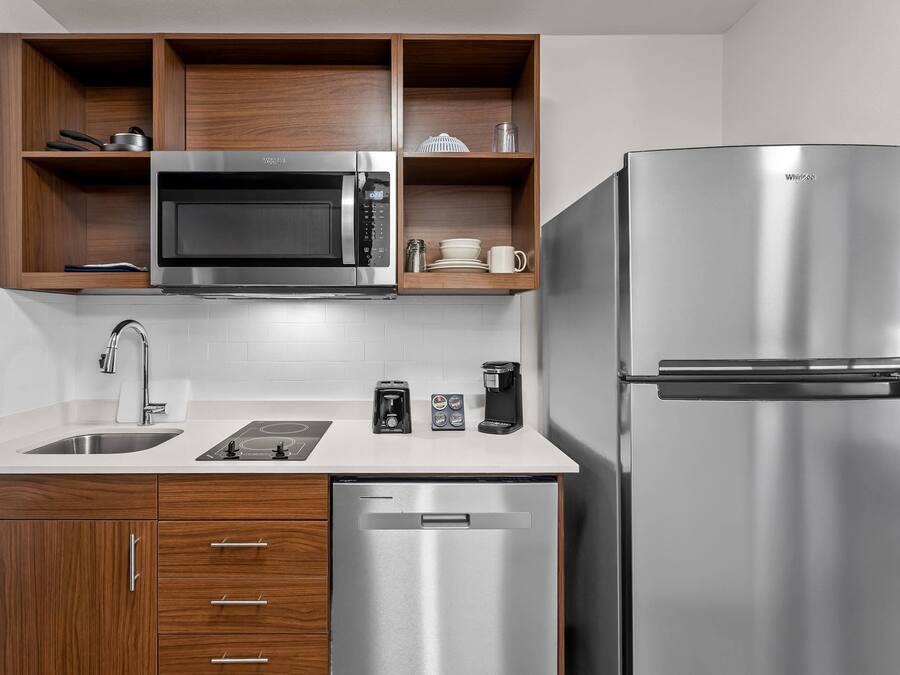 Eine moderne Küche mit eingebauter Mikrowelle, einem Edelstahlkühlschrank und Holzschränken.