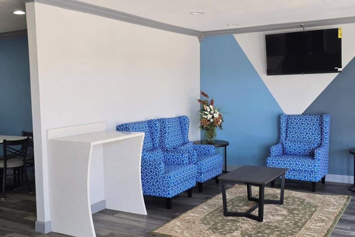A modern lounge area with blue patterned sofas, a small table, and a TV mounted on the wall.