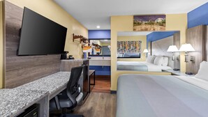 A hotel room with a bed, desk, chair, TV, and a painting on the wall. - Quality Inn & Suites East Point - Atlanta Area (Atlanta)