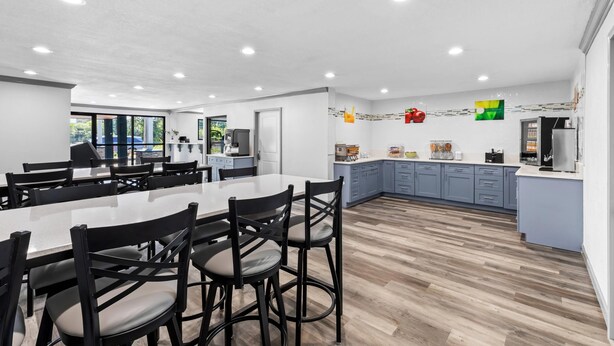 A modern kitchen with a large island, dark wooden flooring, and a view of the outdoors. - Quality Inn & Suites East Point - Atlanta Area (Atlanta)
