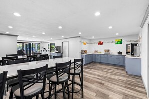A modern kitchen with a large island, dark wooden flooring, and a view of the outdoors. - Quality Inn & Suites East Point - Atlanta Area (Atlanta)