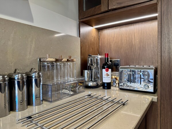 A kitchen with stainless steel appliances, a wine bottle, and a coffee machine. - Southview Terrace, 3 bedroom, Stamford by Belmont Places (Lincolnshire)