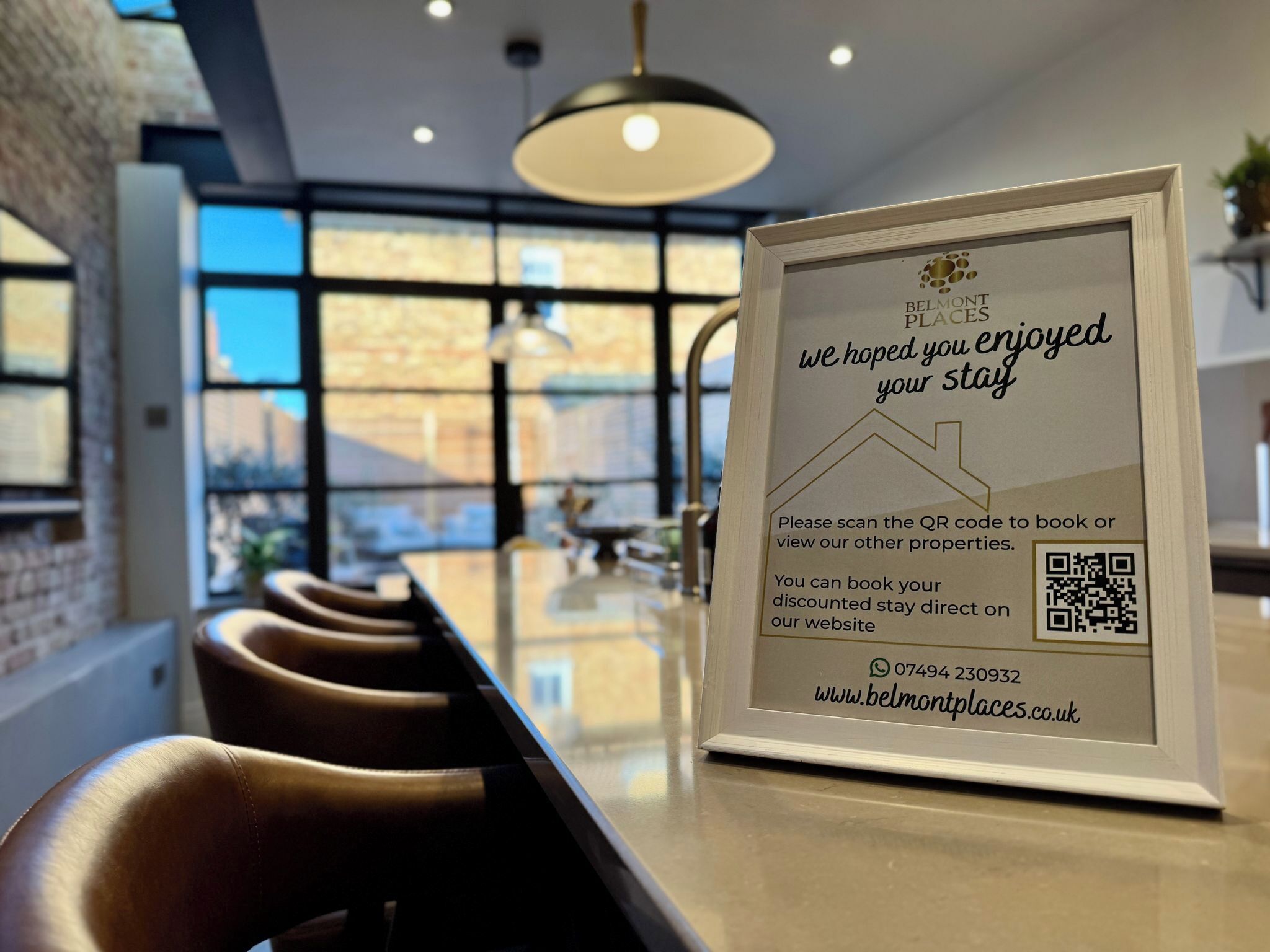 Une affiche encadrée comportant un code QR, l’adresse d’un site web et un numéro de téléphone pour prendre rendez-vous ou visiter des biens immobiliers.