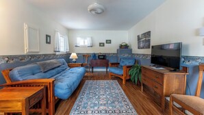 Una sala de estar acogedora con un sofá azul, muebles de madera, un televisor y una alfombra estampada.