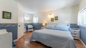 Un dormitorio con una cama grande, una silla, una mesita de noche y una ventana.