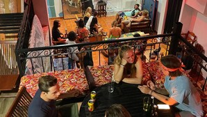 Un groupe de personnes est assis autour d’une table ronde dans une pièce où l’on peut voir une fresque murale, un téléviseur et un ventilateur de plafond.