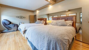 Un dormitorio con dos camas, suelo de madera y techo con vigas a la vista.