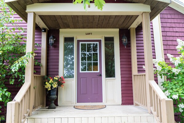 A purple door with a white porch and a flower pot on the steps. - Large Suite in Historic Carriage House! Pet-Friendly! (Bocabec)