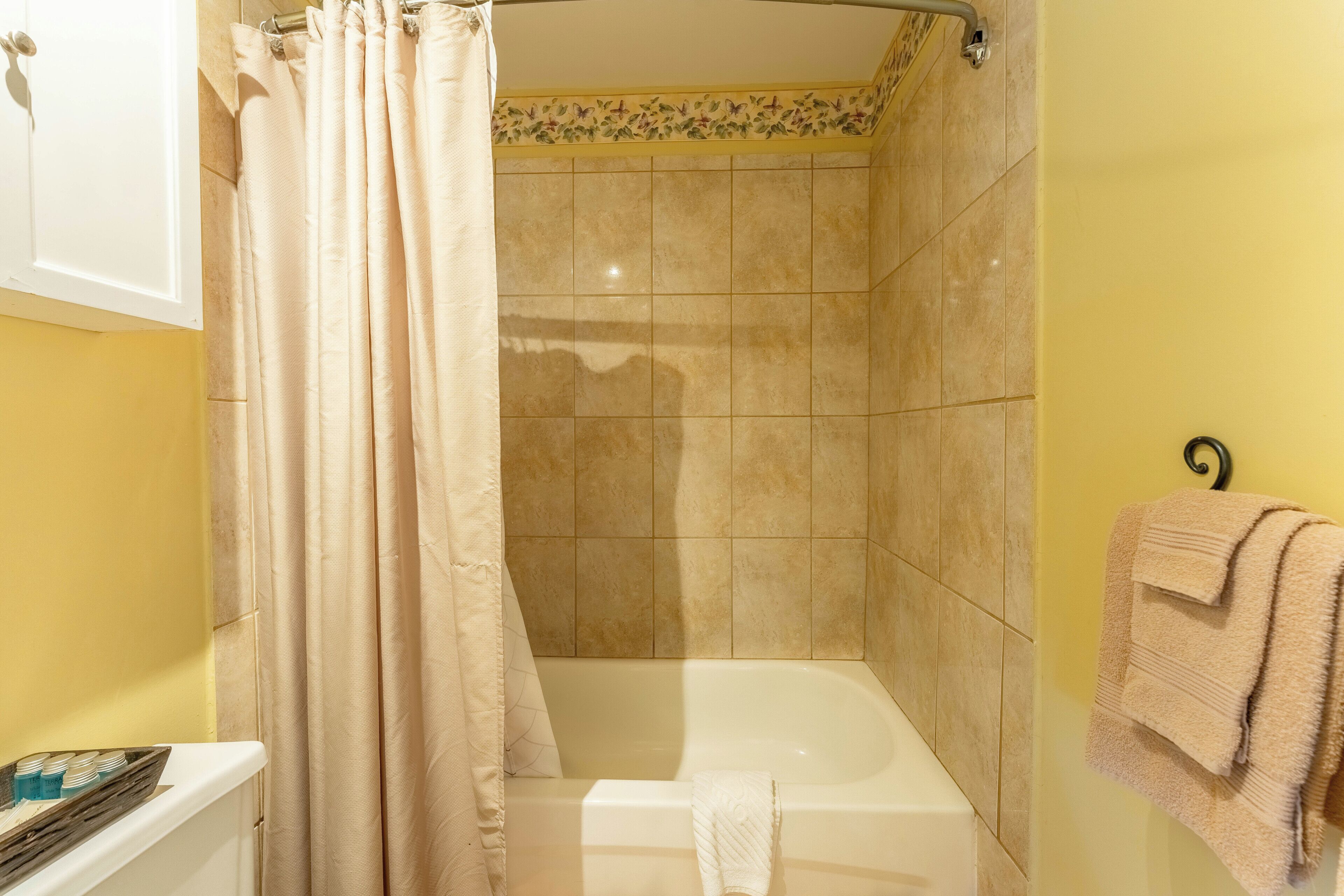 A bathroom with a bathtub, a shower curtain, and a towel rack with towels.