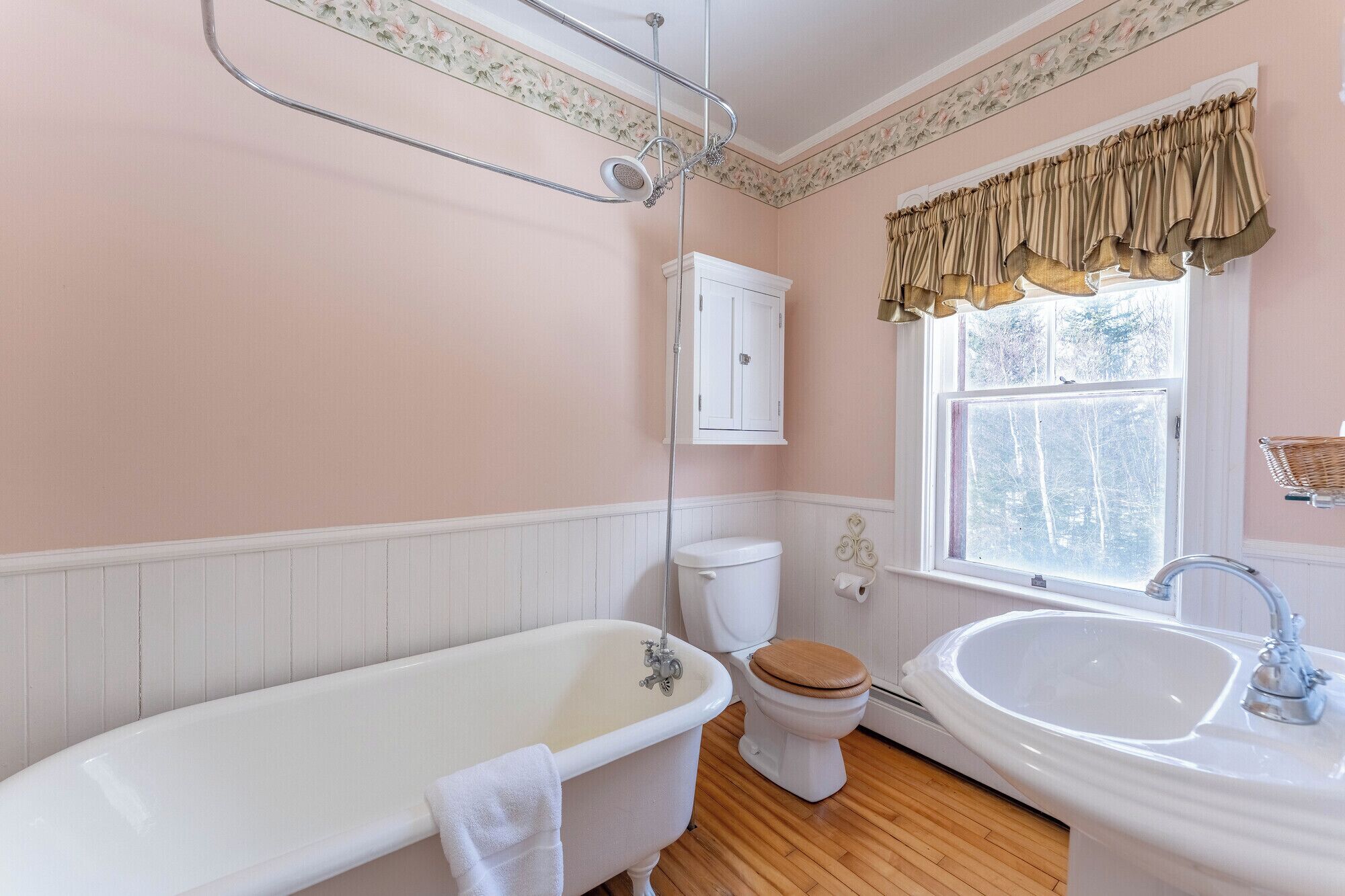 Une salle de bain avec une baignoire sur pieds, des toilettes blanches et un lavabo.