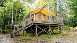 Una cabaña de madera con balcón y escaleras, rodeada de árboles.