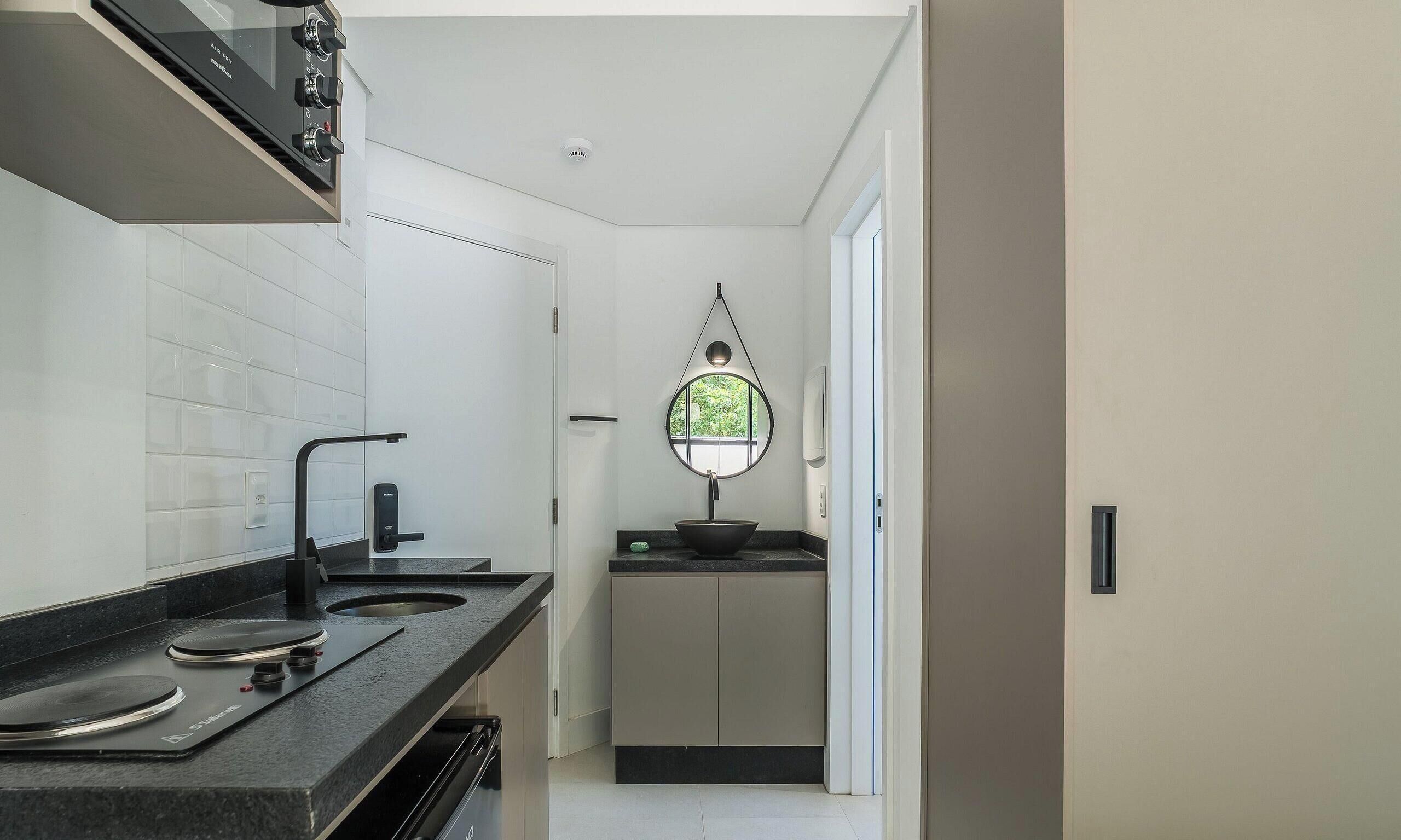 Cocina moderna con encimera negra, estufa y ventana con vistas a zonas verdes.