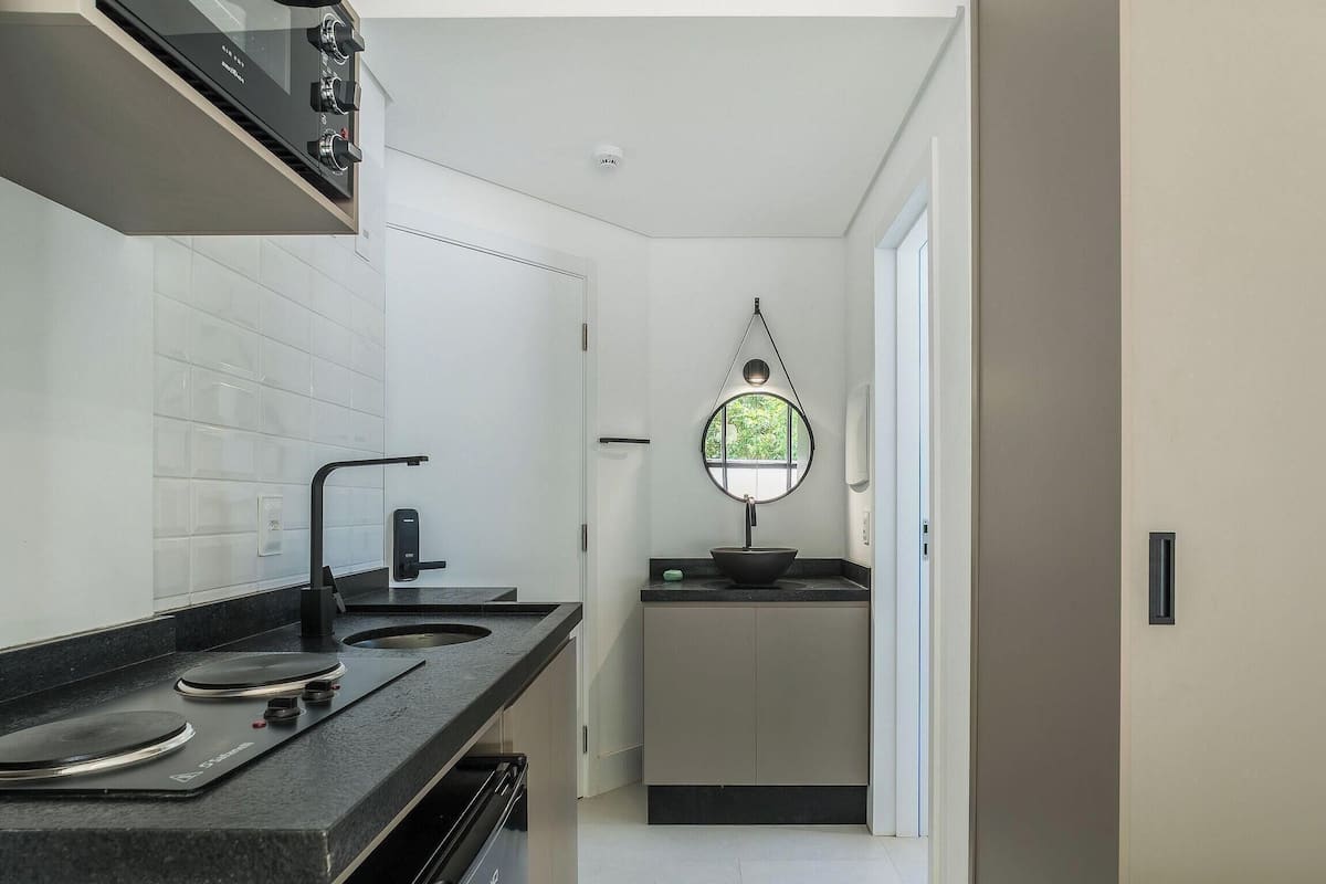 A modern kitchen with a black countertop, a stove, and a window with a view of greenery.