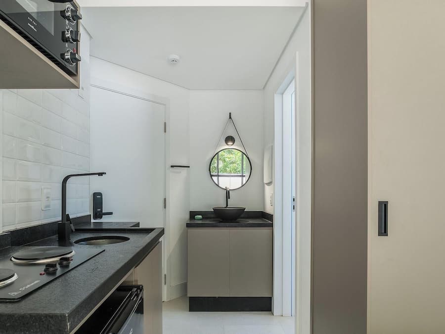 Cocina moderna con horno integrado, lavamanos y ventana con vistas a la vegetación.