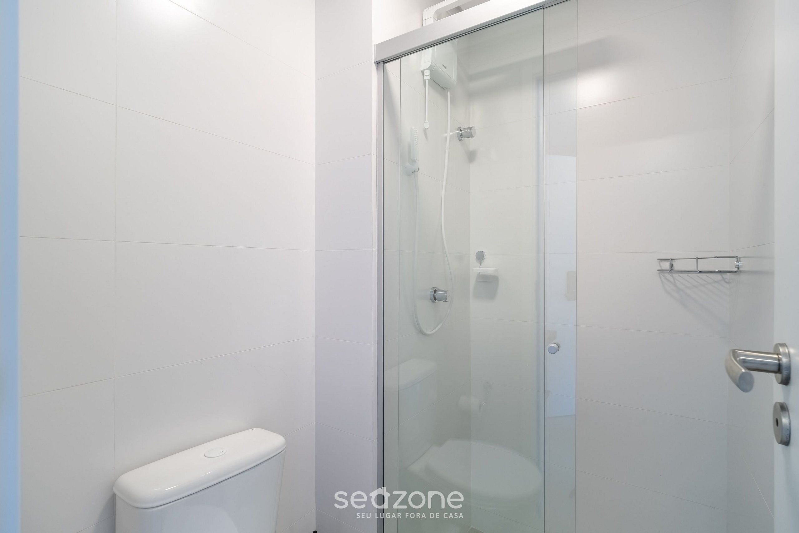 Une salle de bain moderne avec une douche à parois de verre, des toilettes blanches et un sol carrelé.