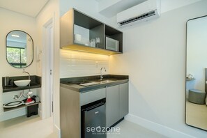 Cocina compacta con lavamanos, microondas y lavavajillas, y un espejo en la pared.