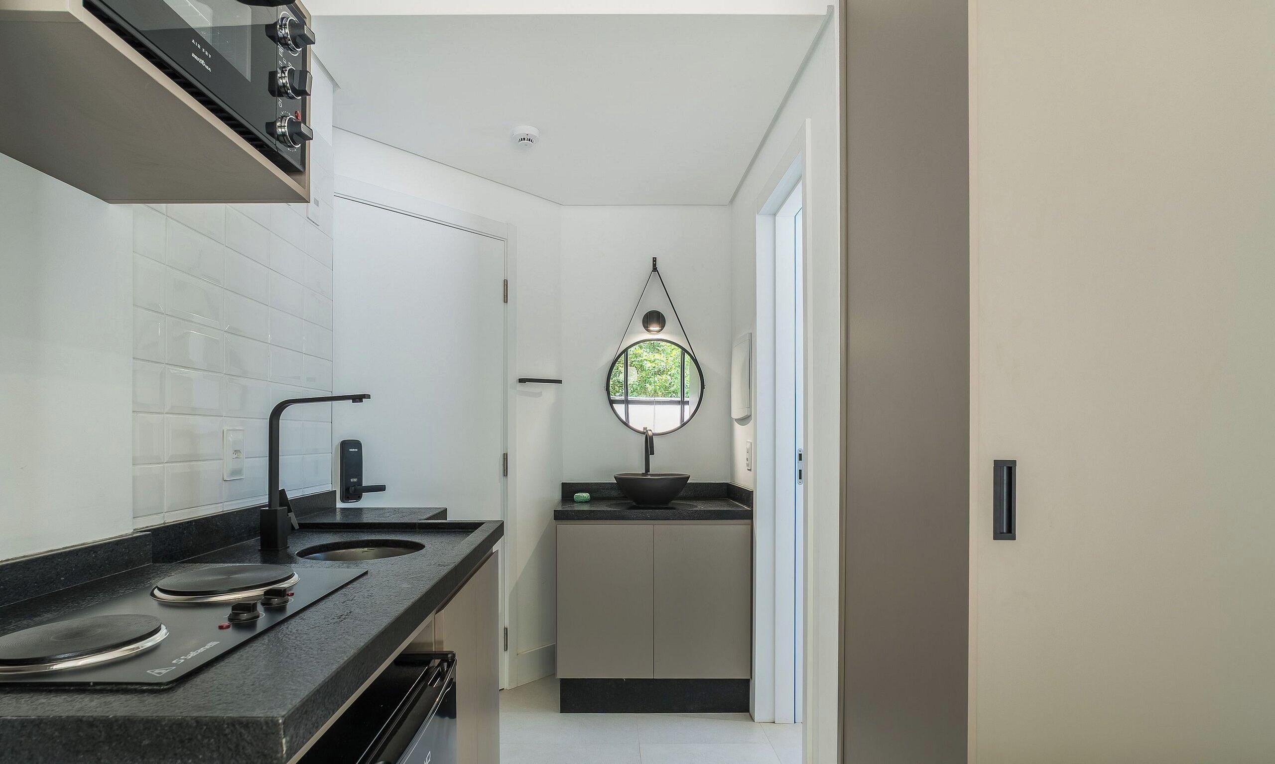 A modern kitchen with a black countertop, a stove, and a small sink.