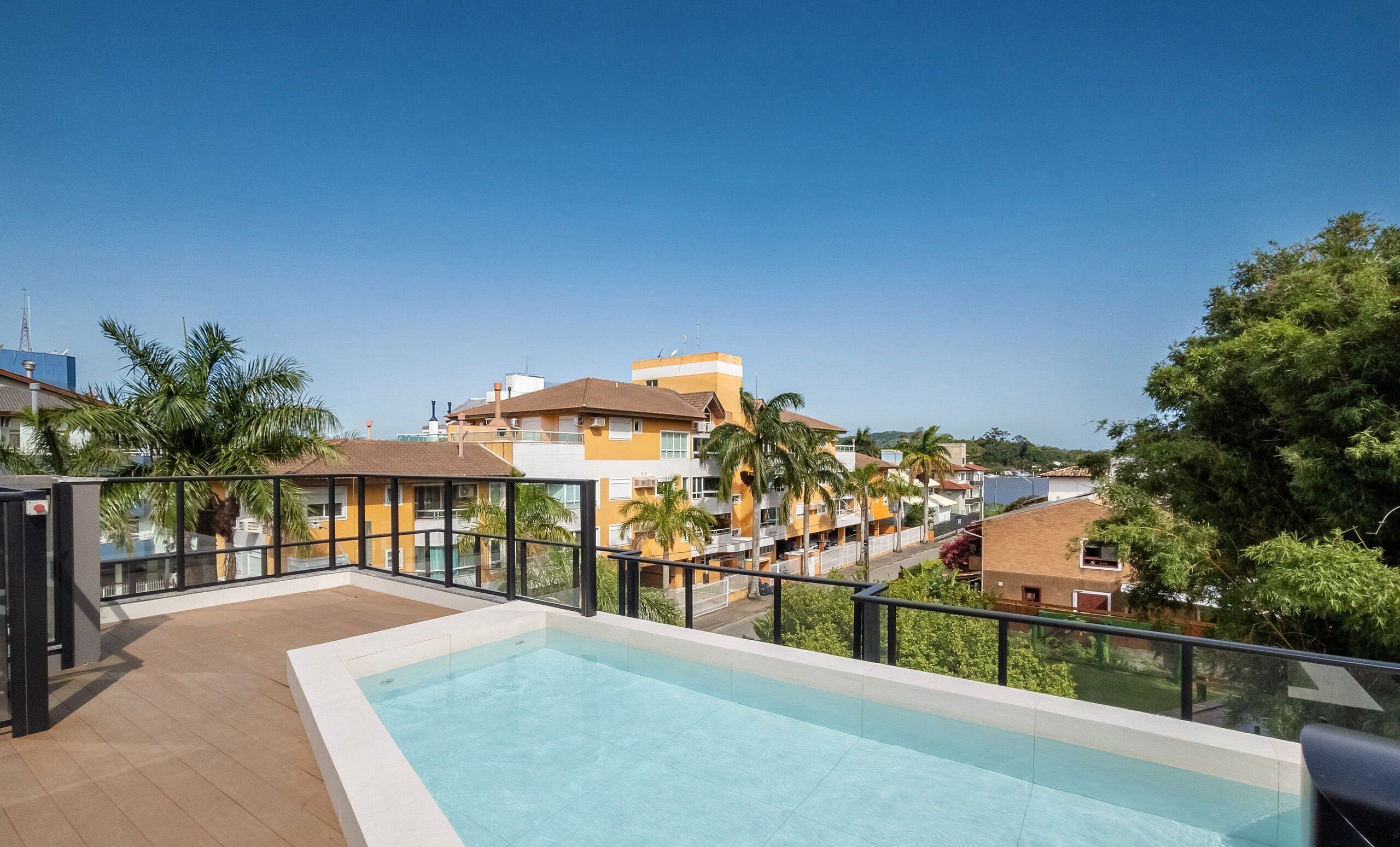 Una piscina en la azotea con vistas despejadas de edificios y palmeras circundantes.