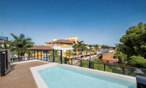 Ein Pool auf dem Dach mit freiem Blick auf umliegende Gebäude und Palmen.