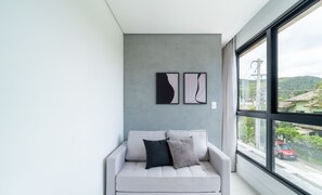 A modern living room with a grey sofa, two abstract wall art pieces, and a large window with a view of a cityscape. - Modern Studios 150m From Lagoa da Conceicao - Lsts II (Florianópolis)