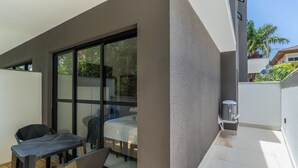 A balcony with a table and chairs, a sliding glass door, and a small air conditioning unit. - Modern Studios 150m From Lagoa da Conceicao - Lsts II (Florianópolis)